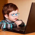 Little boy at a laptop computer wearing glasses