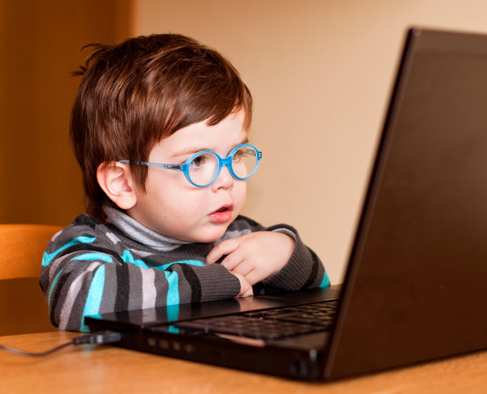 Little boy at a laptop computer wearing glasses