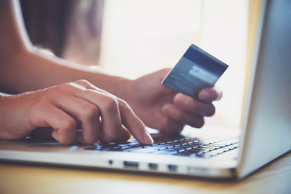 Close up of hands entering a credit card into a laptop