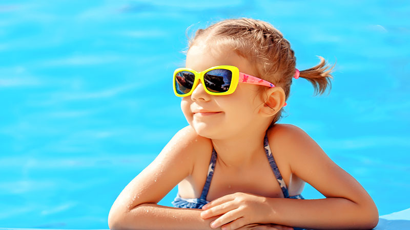 Young girl in a pool with sunglasses on